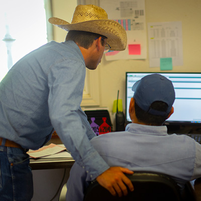 Two male Friona employees looking at computer